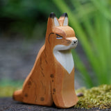 An Ostheimer sitting lynx figure placed on a mossy surface outdoors. This expertly hand crafted wooden figure is part of a large range of wooden toys here at Babipur. 