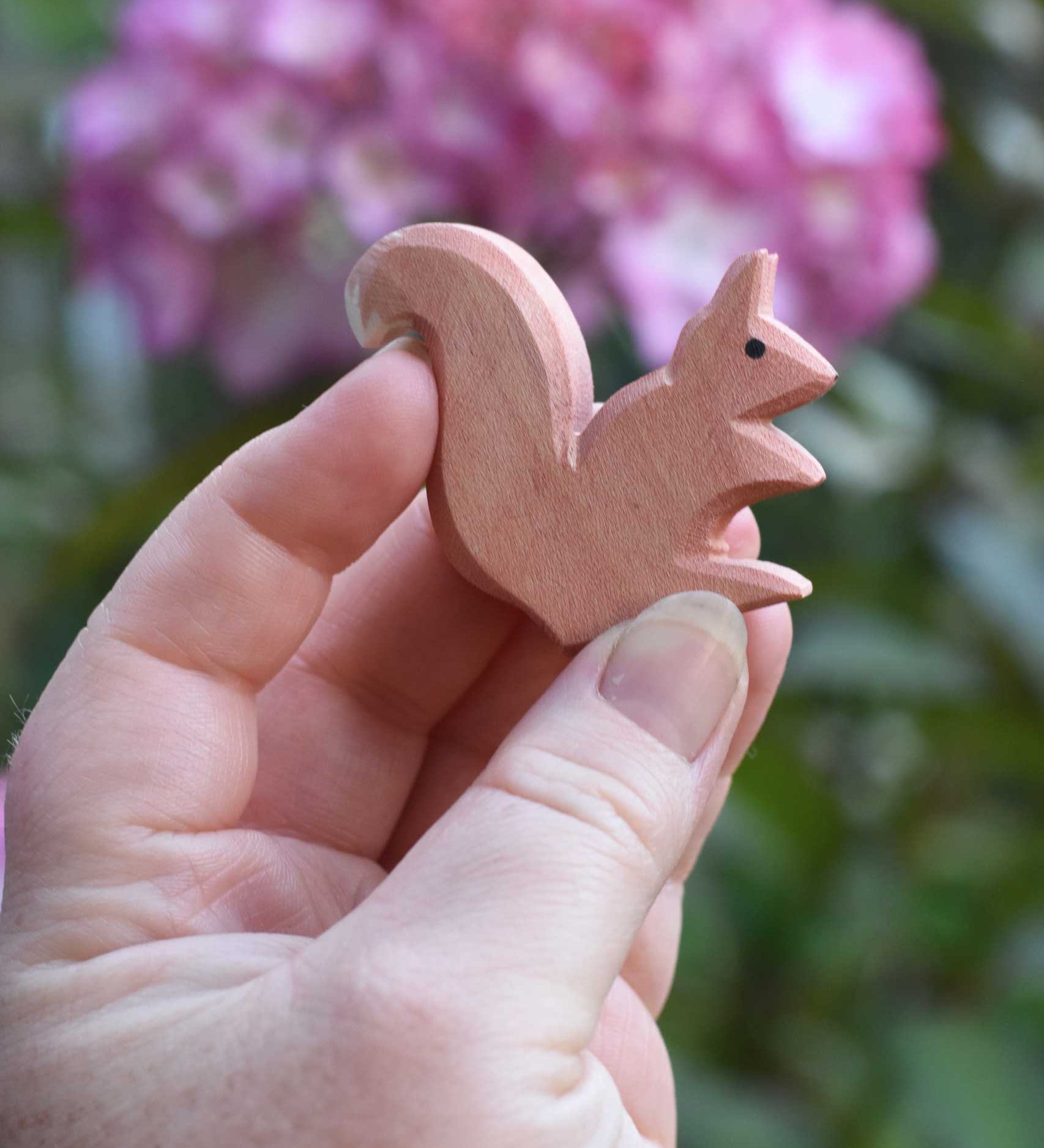 An Ostheimer Sitting Red Squirrel wooden toy figure shown in an adult's hand for scale. Check out our full range of expertly crafted wooden toy figures here at Babipur.
