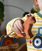 Ostheimer sitting tiger wooden toy figure in a child's hand. 