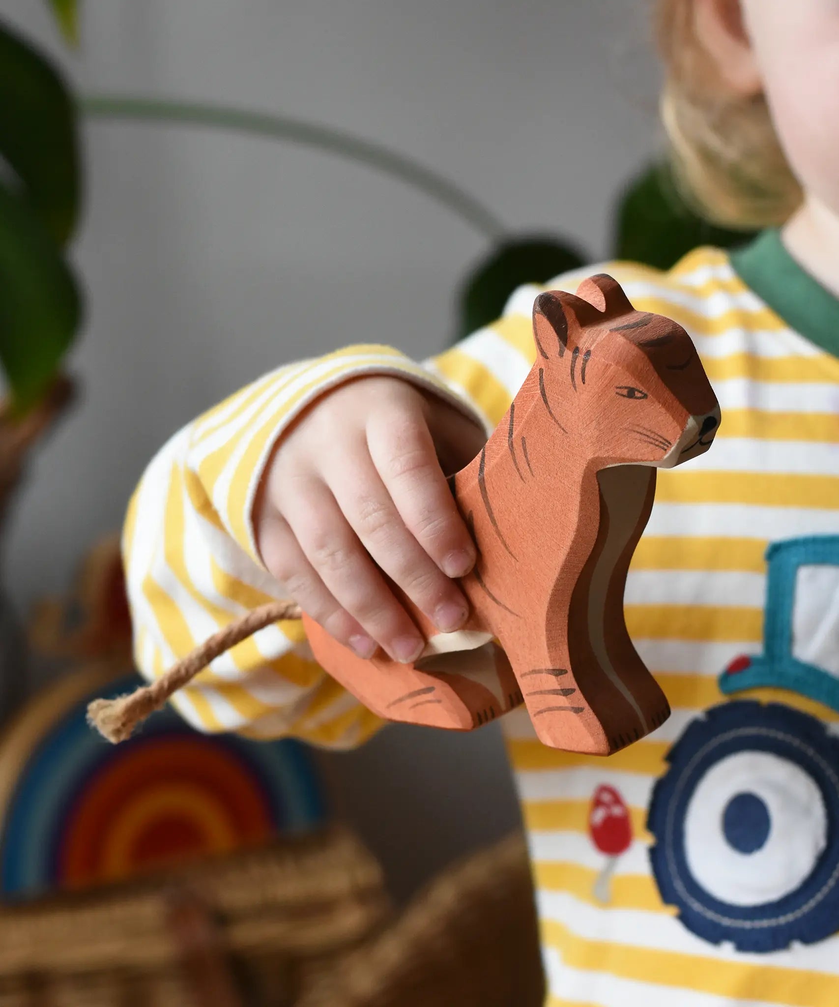 Ostheimer sitting tiger wooden toy figure in a child's hand. 