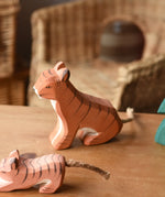 Ostheimer sitting tiger wooden toy figure placed on a wooden surface.