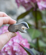 A small Ostheimer wooden toy badger figure shown in an adult's hand for scale. 