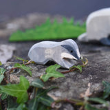 An Ostheimer small wooden badger figure placed on a stone wall outdoors. Check out our full range of wooden toy figures at Babipur.