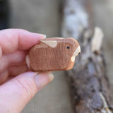 A small brown Ostheimer rabbit figure shown in an adult's hand for scale. Check out our full range of expertly crafted wooden toy figures and scenery here at Babipur.
