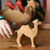 Child's hand reaching for the Ostheimer small camel wooden toy figure. 