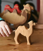 Child's hand reaching for the Ostheimer small camel wooden toy figure. 