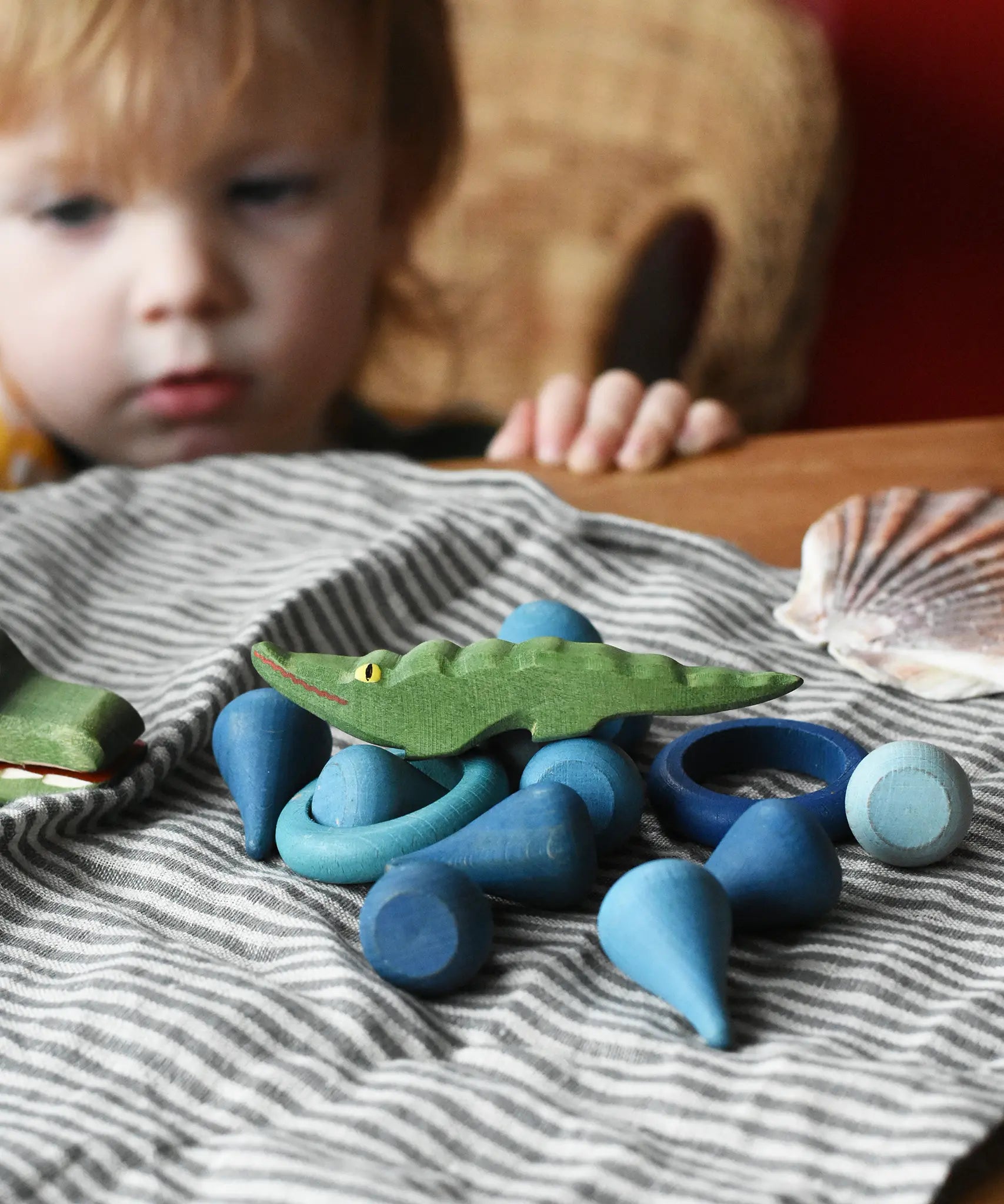 Small Ostheimer crocodile placed on a pile of blue coloured Grapat mandala pieces and rings.