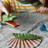 Small Ostheimer crocodile placed on a shell, a child in the background is holding the large crocodile figure. 