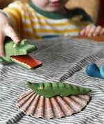 Small Ostheimer crocodile placed on a shell, a child in the background is holding the large crocodile figure. 