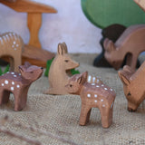 An Ostheimer Small Deer With Head Low placed in a small world play scene with lots of other deer and fawn figures. Ostheimer wooden toy figures and scenery are available at Babipur. 