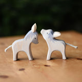Two Ostheimer small wooden donkey wooden toy figures placed on a wooden surface.  Ostheimer's range of hand crafted, heirloom quality wooden toys are available to buy at Babipur. 