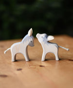 Two Ostheimer small wooden donkey wooden toy figures placed on a wooden surface.  Ostheimer's range of hand crafted, heirloom quality wooden toys are available to buy at Babipur. 