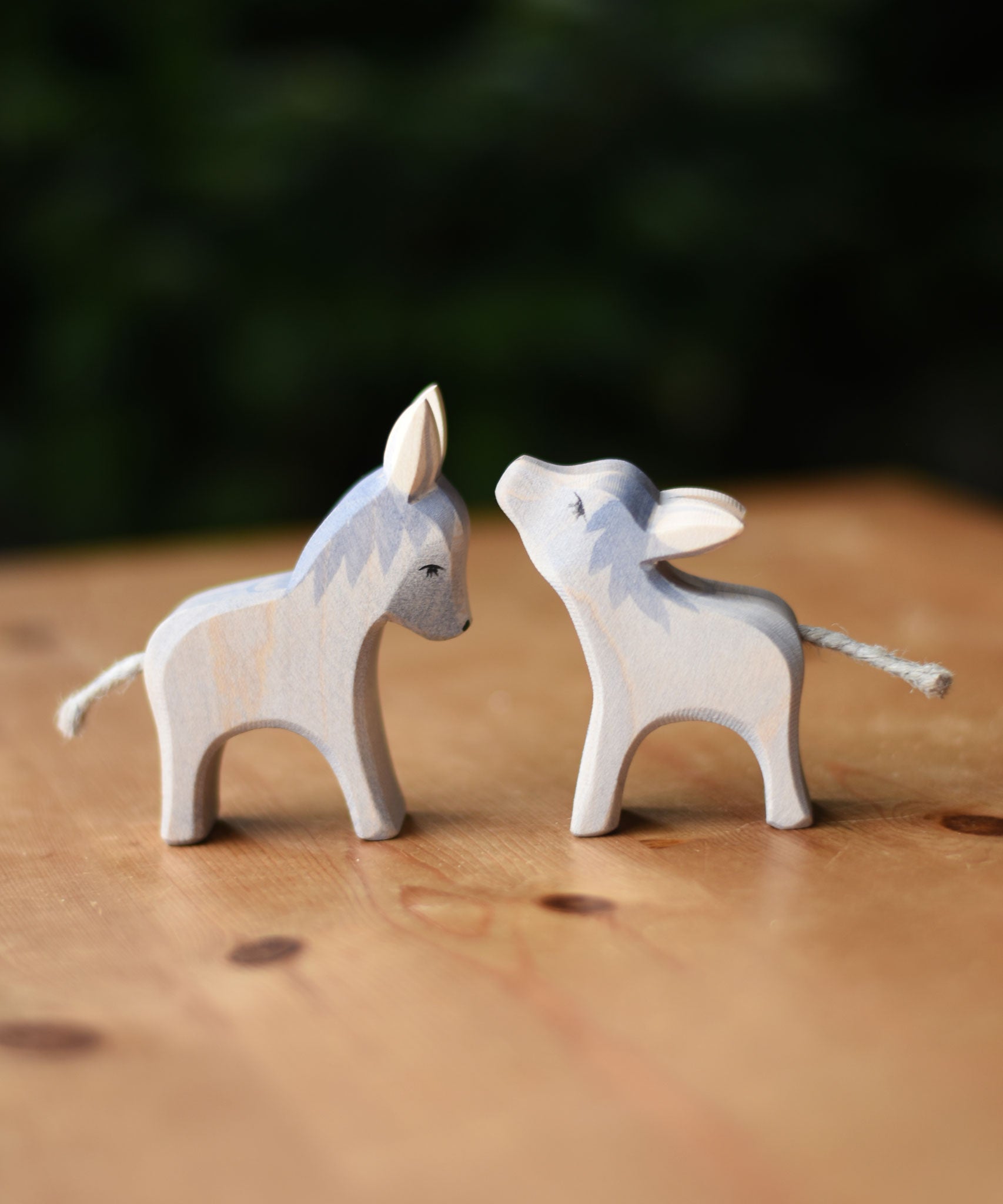 Two Ostheimer small wooden donkey wooden toy figures placed on a wooden surface.  Ostheimer's range of hand crafted, heirloom quality wooden toys are available to buy at Babipur. 