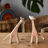 Ostheimer small giraffes wooden toy figures one with head low and one with head high placed next to each other.