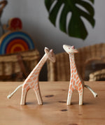 Ostheimer small giraffes wooden toy figures one with head low and one with head high placed next to each other.