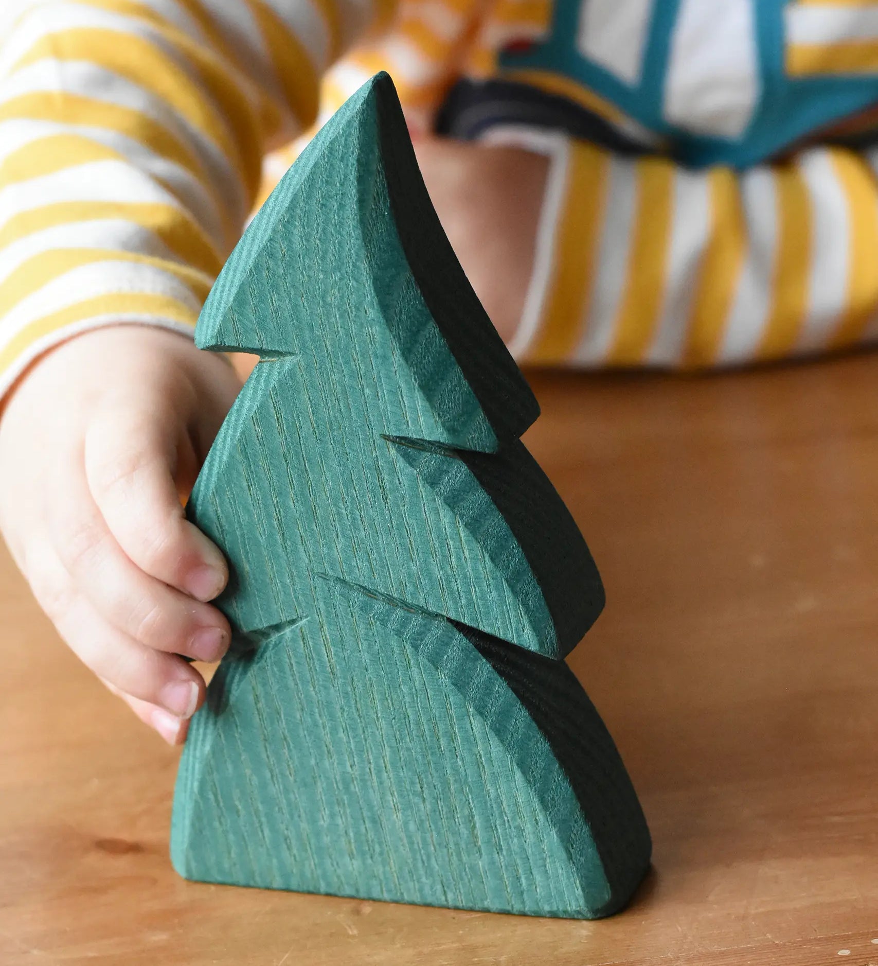 Child's hand reaching for the Ostheimer small green spruce tree. 