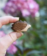 A small hedgehog wooden toy figure shown in an adult's hand to show scale. Check out our full range of expertly crafted wooden toy figures and scenery here at Babipur.