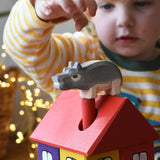 Ostheimer small hippopotamus wooden toy figure placed on the roof of the coloured house by a child. 