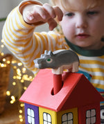 Ostheimer small hippopotamus wooden toy figure placed on the roof of the coloured house by a child. 