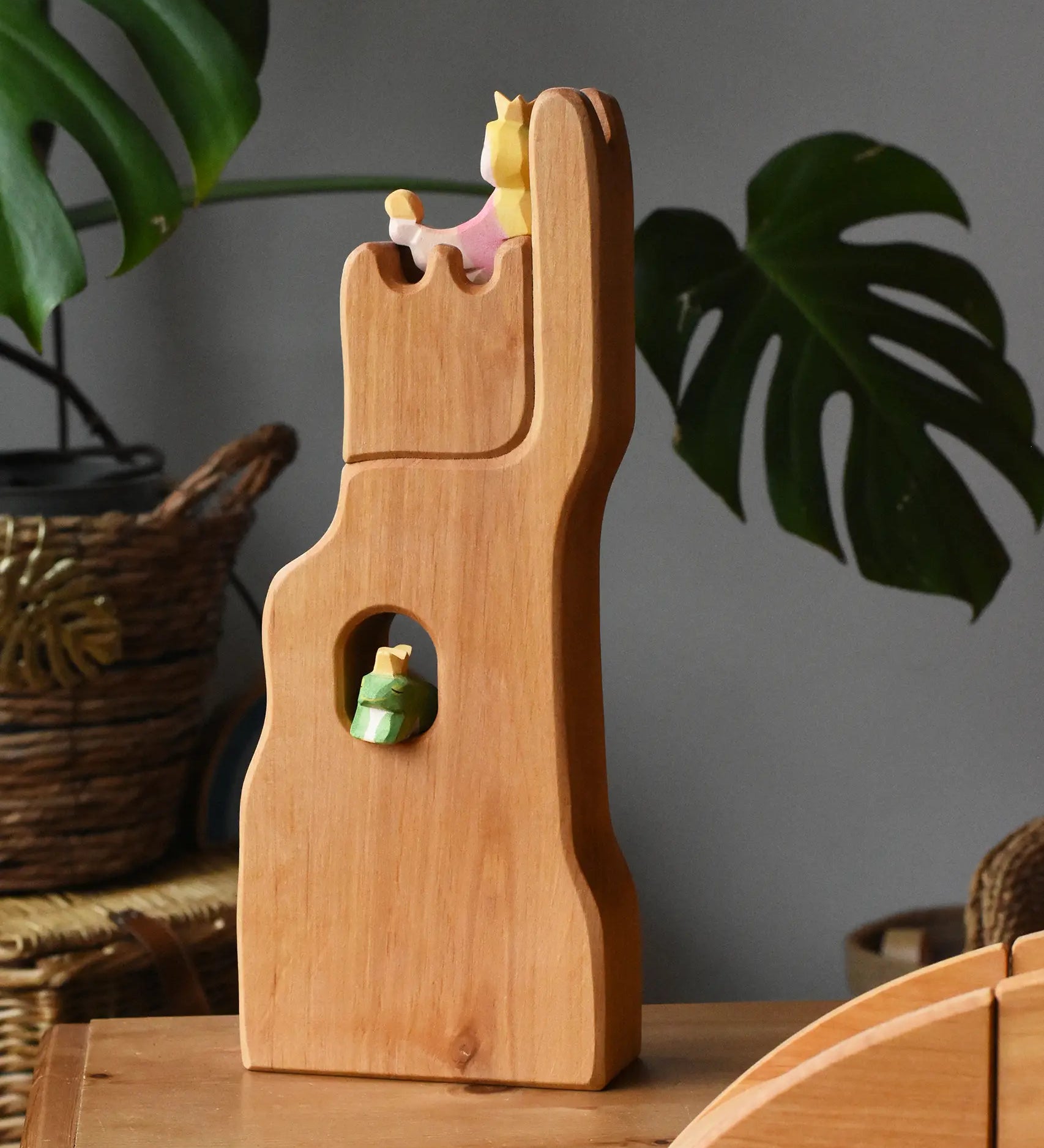 Ostheimer small wooden lookout tower wooden toy placed in a small world play scene with a princess in the tower and a frog king in the window. 