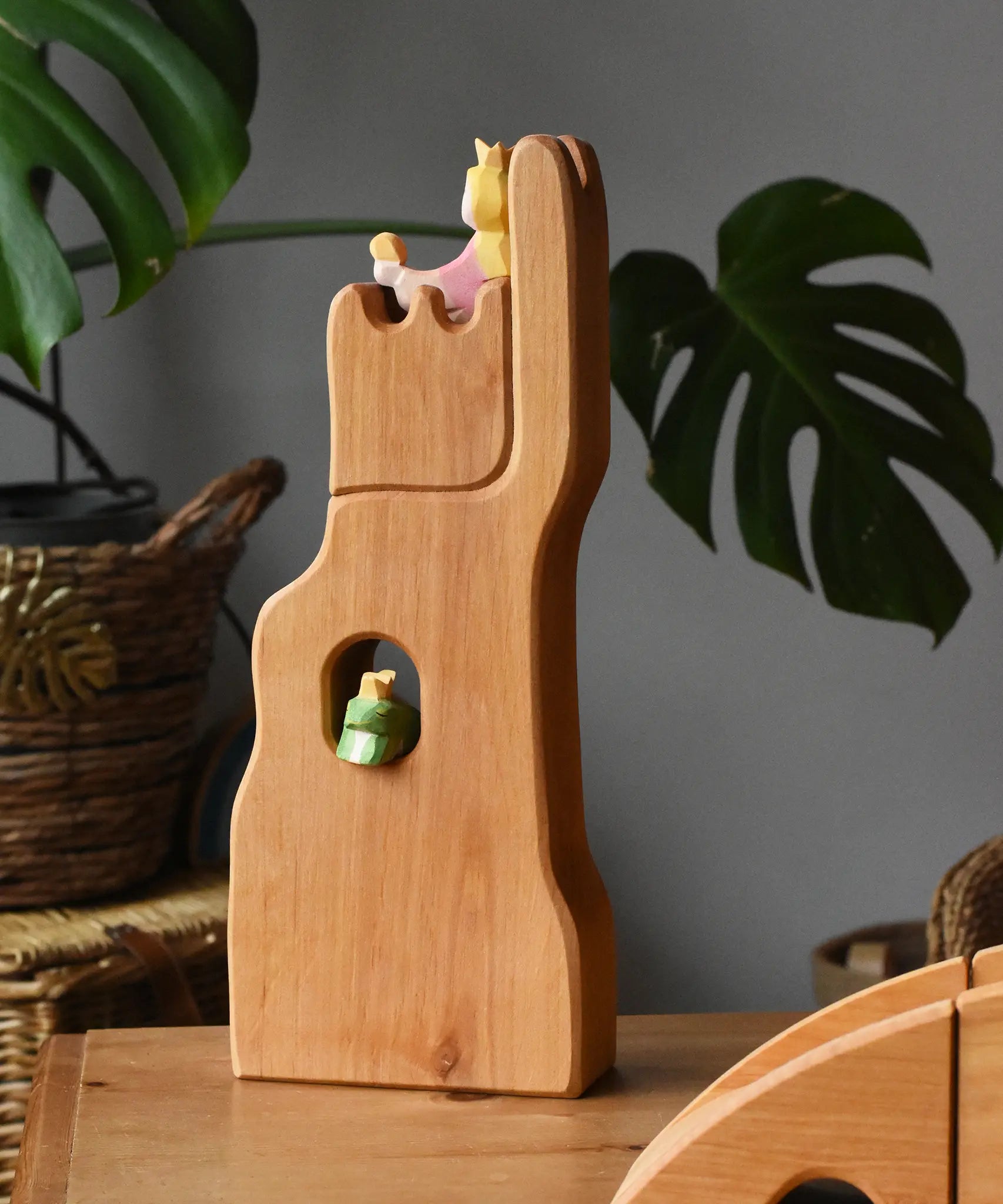 Ostheimer small wooden lookout tower wooden toy placed in a small world play scene with a princess in the tower and a frog king in the window. 