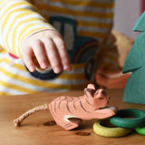 Child's hand reaching for the Ostheimer lurking small tiger wooden toy figure.