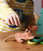 Child's hand reaching for the Ostheimer lurking small tiger wooden toy figure.