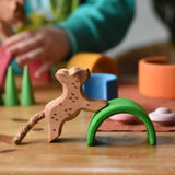 Ostheimer small running leopard wooden toy figure placed on the green arch from the Grimm's mini rainbow. 