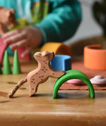 Ostheimer small running leopard wooden toy figure placed on the green arch from the Grimm's mini rainbow. 