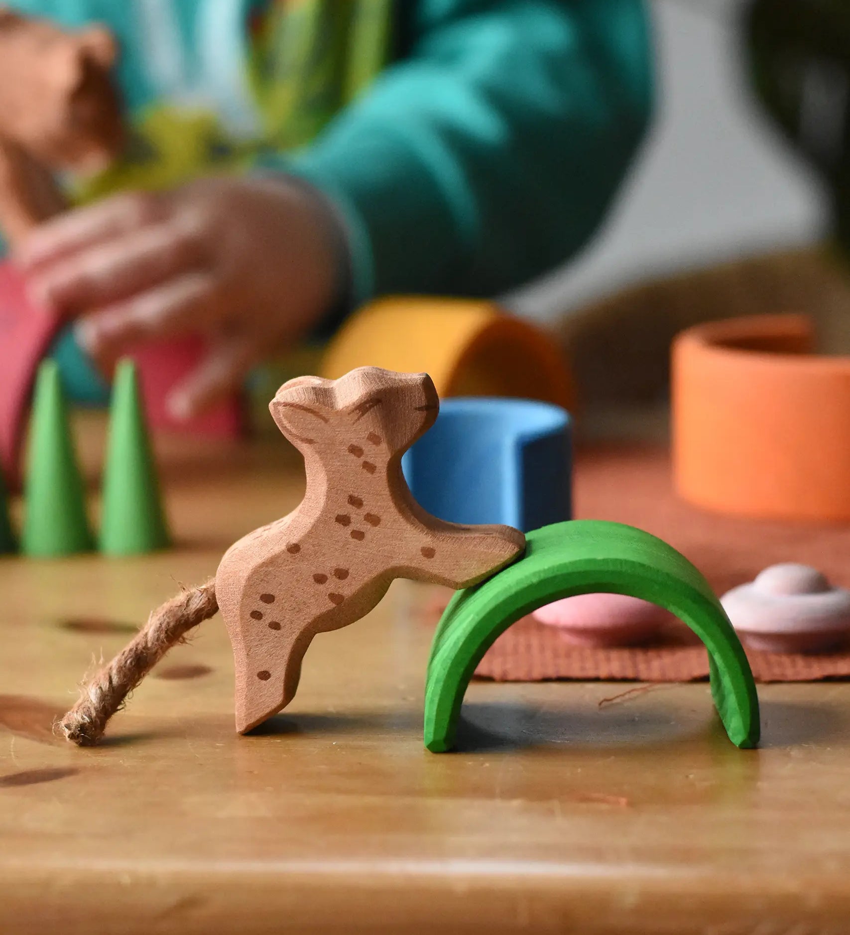 Ostheimer small running leopard wooden toy figure placed on the green arch from the Grimm's mini rainbow. 