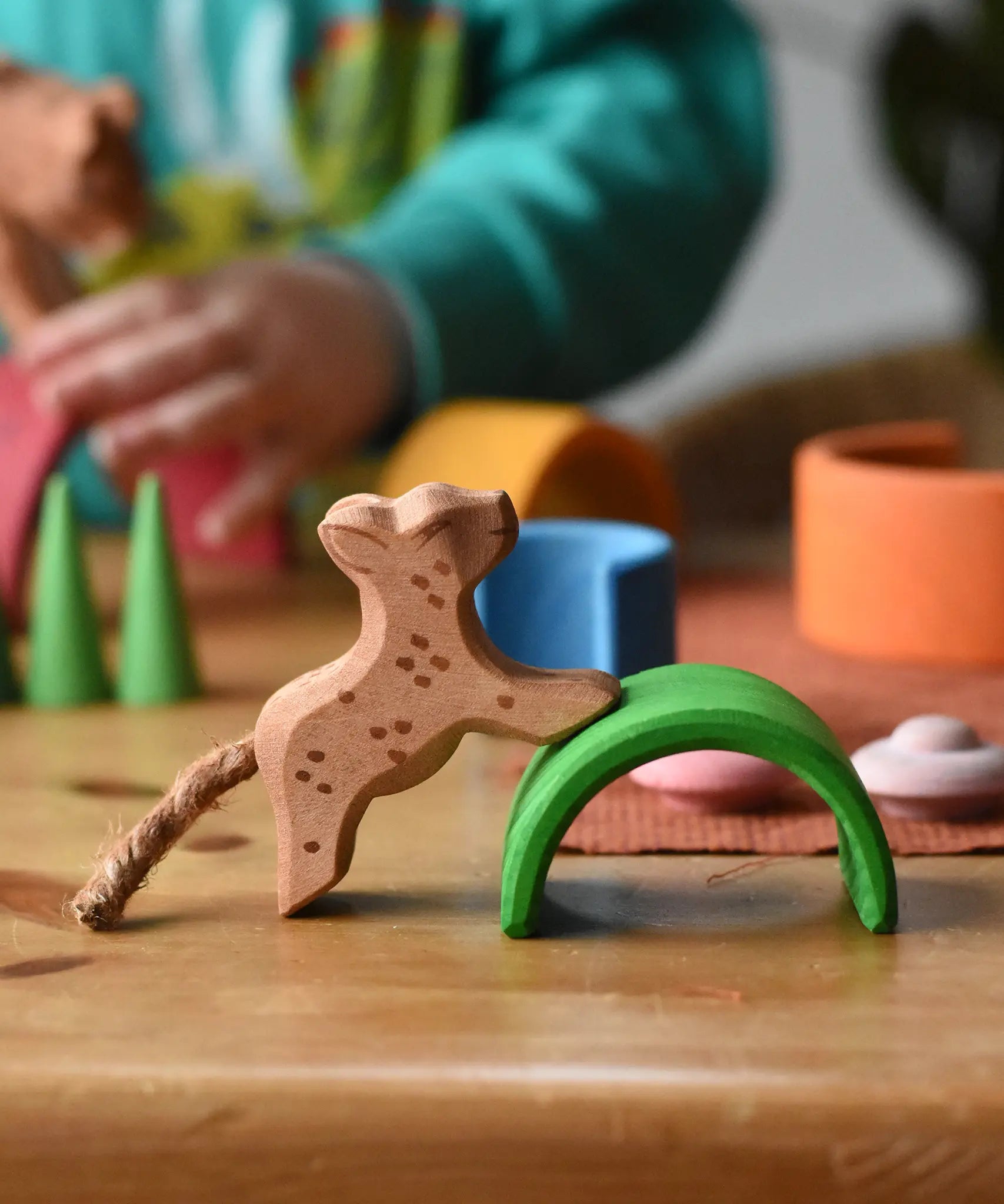 Ostheimer small running leopard wooden toy figure placed on the green arch from the Grimm's mini rainbow. 