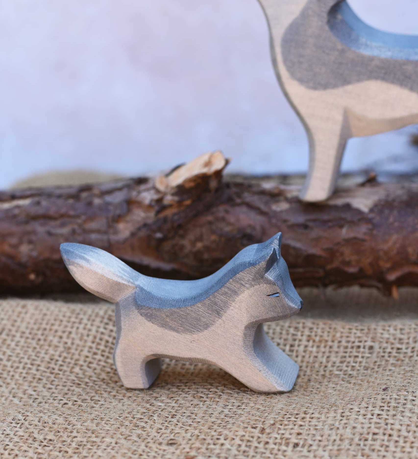 A close up of the small running Osthimer wolf figure placed in a small world play scene. Check out our full range of expertly crafted wooden toy figures and scenery here at Babipur.