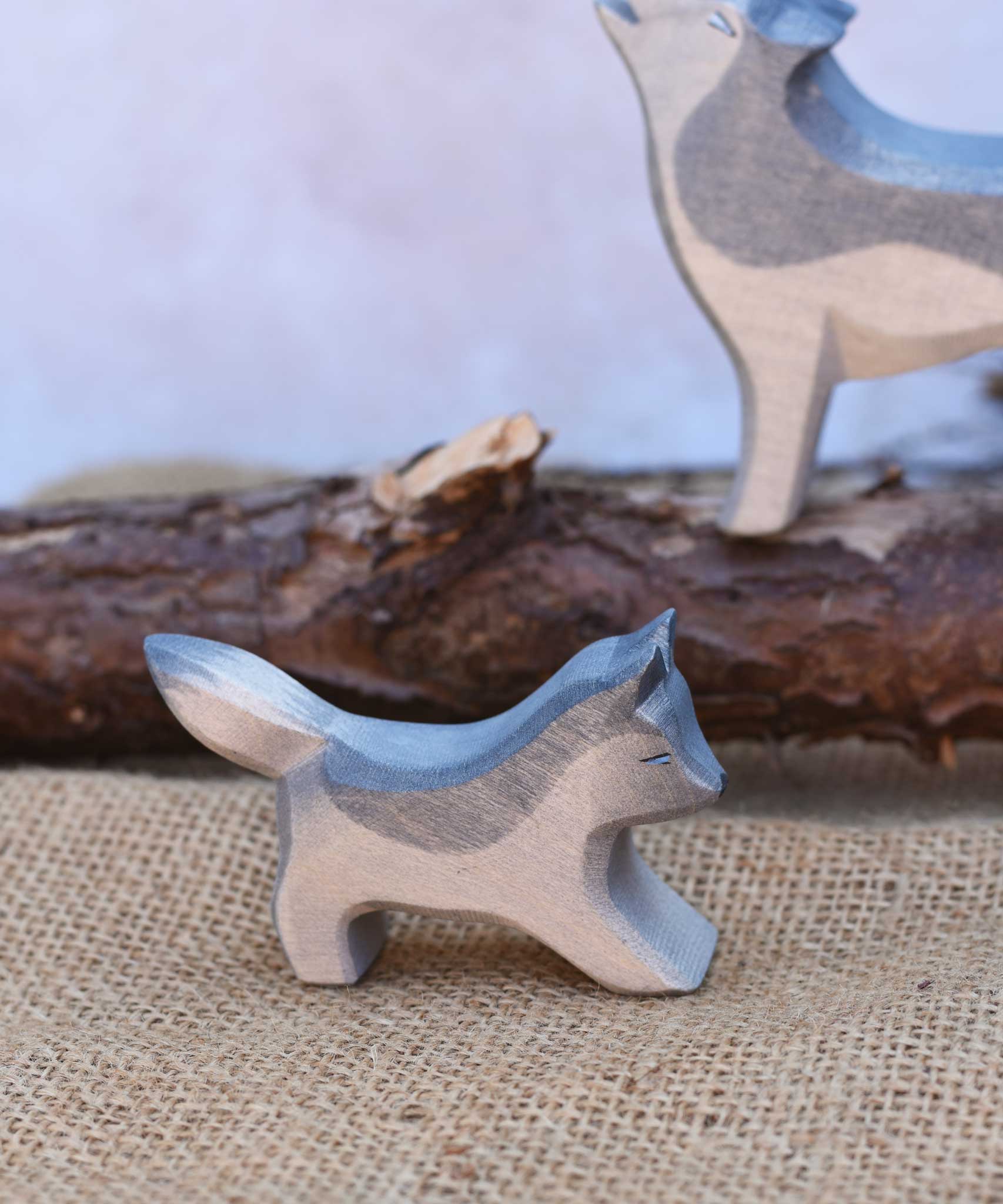 A close up of the small running Osthimer wolf figure placed in a small world play scene. Check out our full range of expertly crafted wooden toy figures and scenery here at Babipur.
