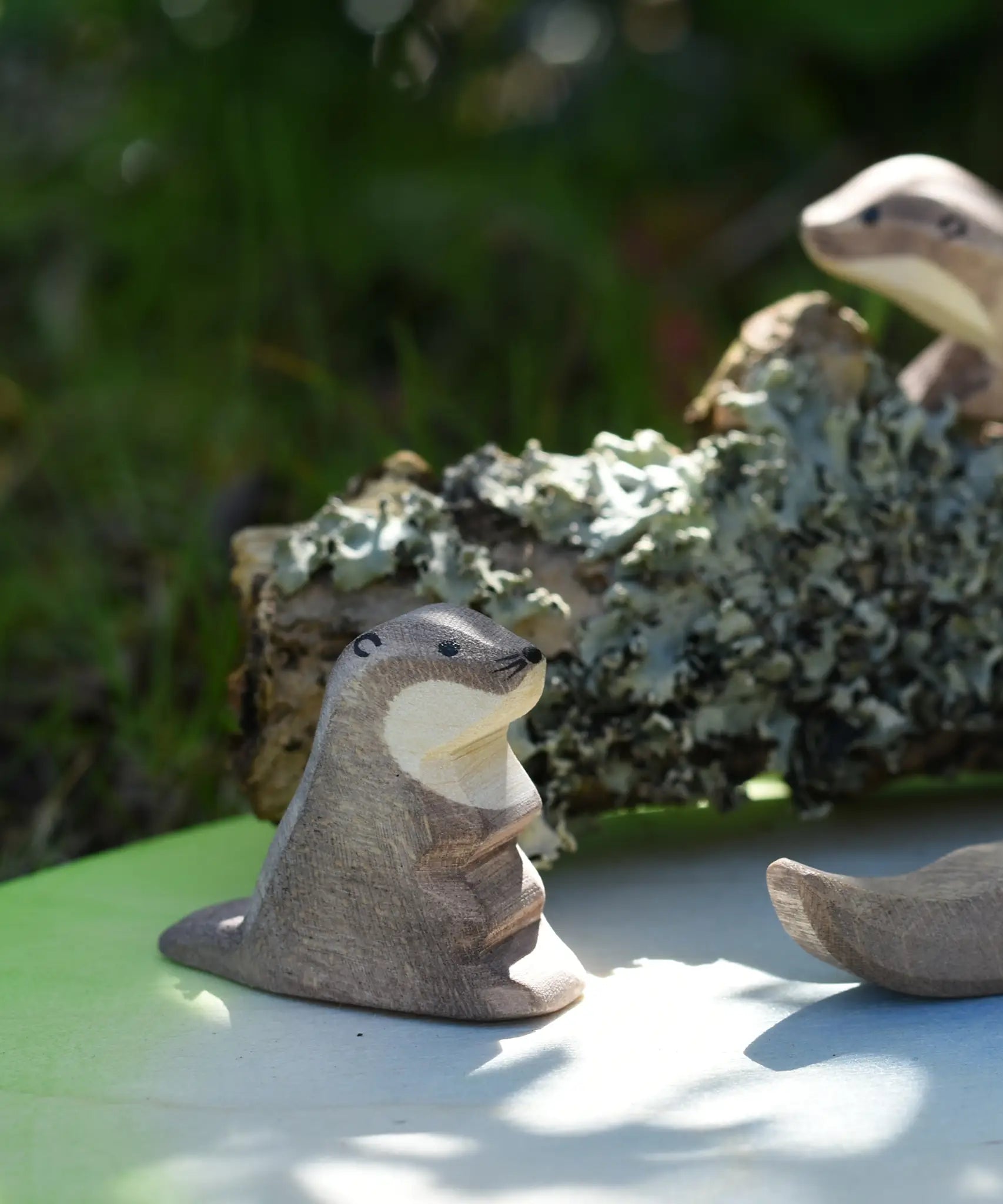 Ostheimer small  sea otter wooden toy figure placed on a pond play scenery piece in a small world play set up.
