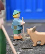 Ostheimer small shepherd boy wooden toy figure placed on a stone wall with a German shepherd blurred in the foreground. 