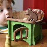 Ostheimer small sitting brown bear wooden toy figure placed on the roof of a green hutch toy with a Grapat animal Nin placed in front of the hutch. 