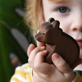 Ostheimer small sitting brown bear wooden toy figure in a child's hands. 