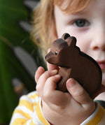 Ostheimer small sitting brown bear wooden toy figure in a child's hands. 