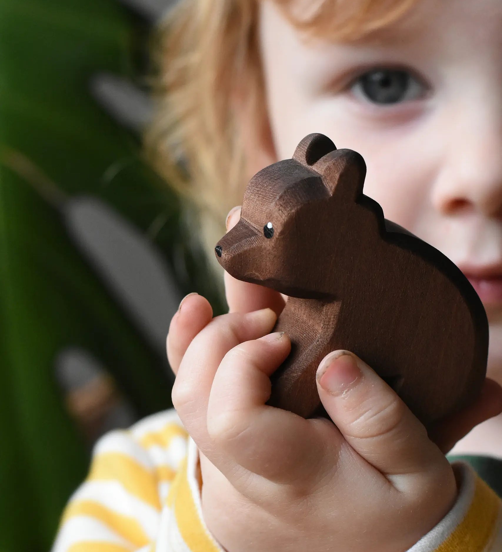 Ostheimer small sitting brown bear wooden toy figure in a child's hands. 