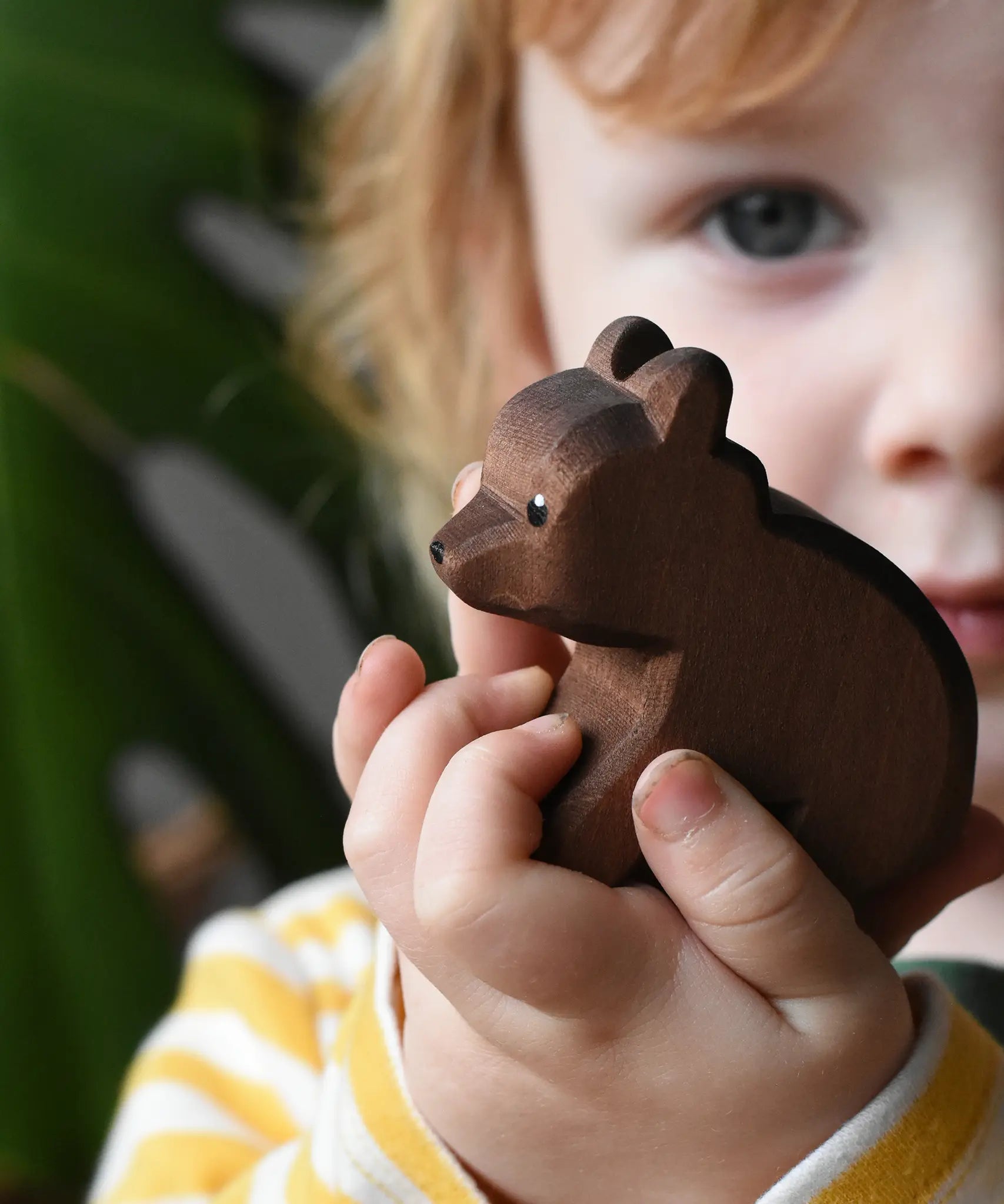 Ostheimer small sitting brown bear wooden toy figure in a child's hands. 