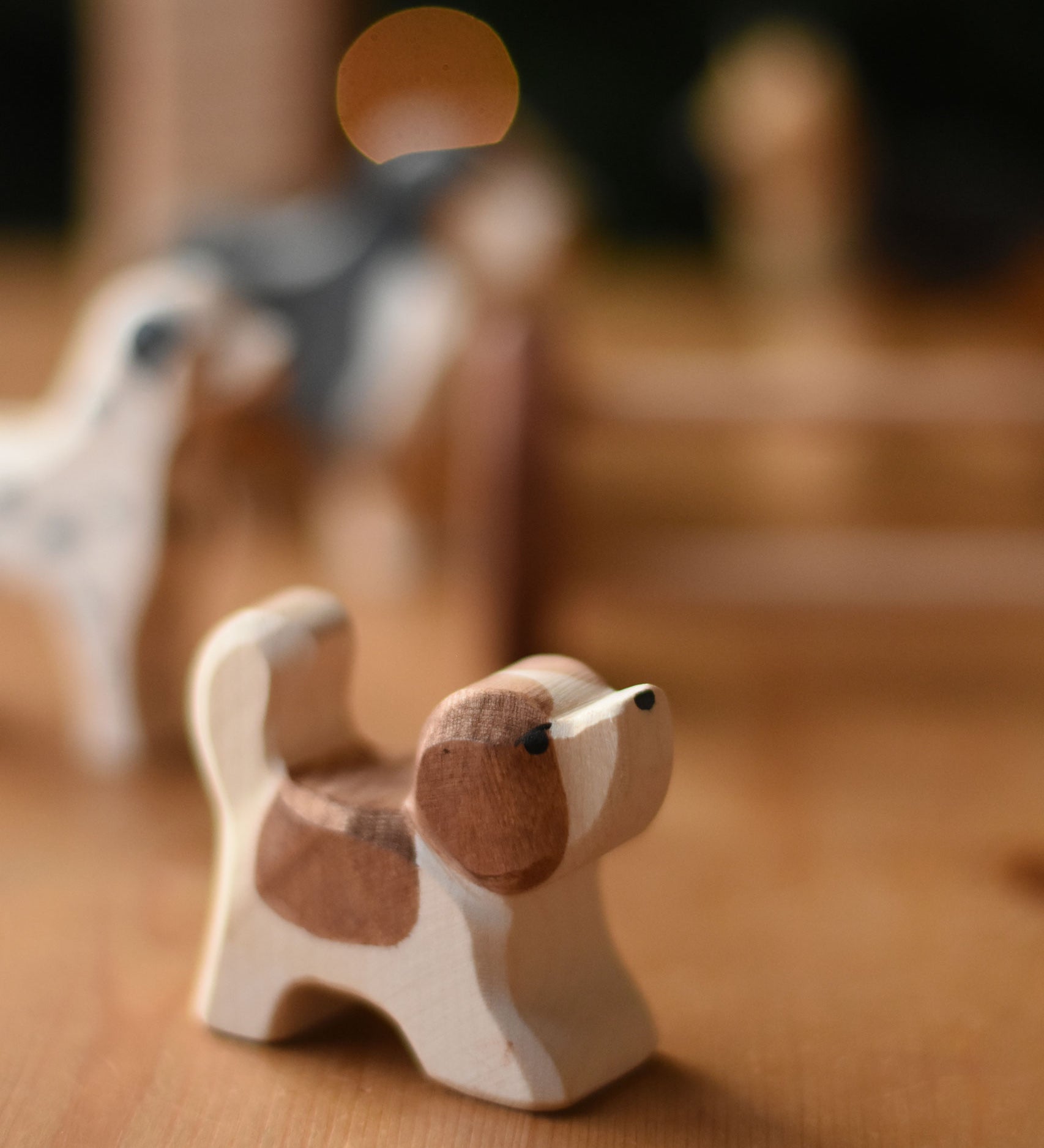 An Ostheimer small St Bernard dog wooden toy figure placed on a wooden surface. These wooden figures are part of a wide range of expertly hand crafted wooden toys here at Babipur. 