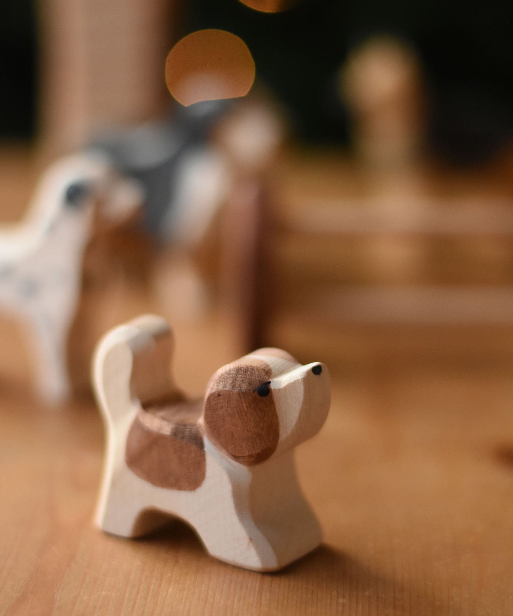 An Ostheimer small St Bernard dog wooden toy figure placed on a wooden surface. These wooden figures are part of a wide range of expertly hand crafted wooden toys here at Babipur. 