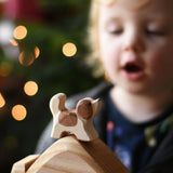 An Ostheimer small St Bernard dog wooden toy figure placed on a wooden house shaped piece. A child can be seen in the background. These wooden figures are part of a wide range of expertly hand crafted wooden toys here at Babipur. 