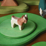 Ostheimer small standing brown and white goat wooden toy figure on green meadow plates. 