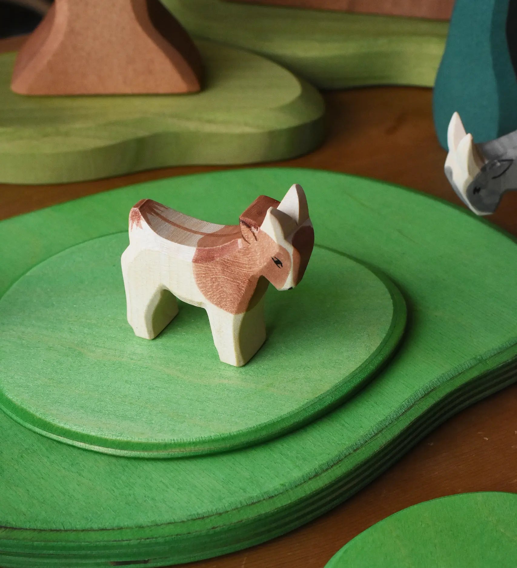 Ostheimer small standing brown and white goat wooden toy figure on green meadow plates. 