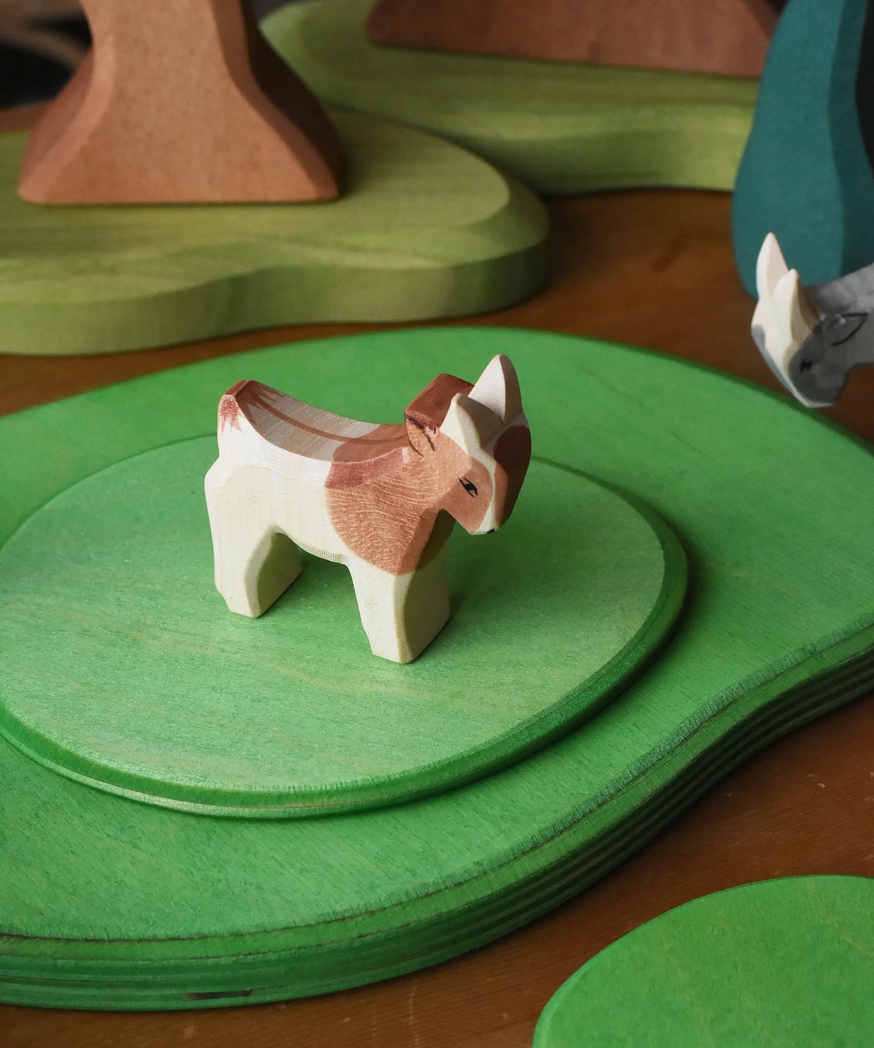 Ostheimer small standing brown and white goat wooden toy figure on green meadow plates. 