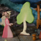 A small Ostheimer birch tree placed on a wooden surface in the middle of a small world play scene next to a lady-in-waiting-figure. These wooden figures are part of a wide range of expertly hand crafted wooden toys here at Babipur. 
