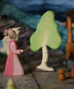 A small Ostheimer birch tree placed on a wooden surface in the middle of a small world play scene next to a lady-in-waiting-figure. These wooden figures are part of a wide range of expertly hand crafted wooden toys here at Babipur. 