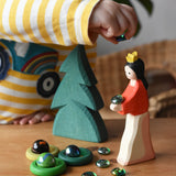 Ostheimer snow white wooden toy figure placed in a small world play scene with a small spruce tree, Billes flat marbles and green Grapat rings.