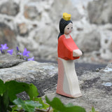 Ostheimer Snow White wooden toy figure placed on a stone wall outdoors. 